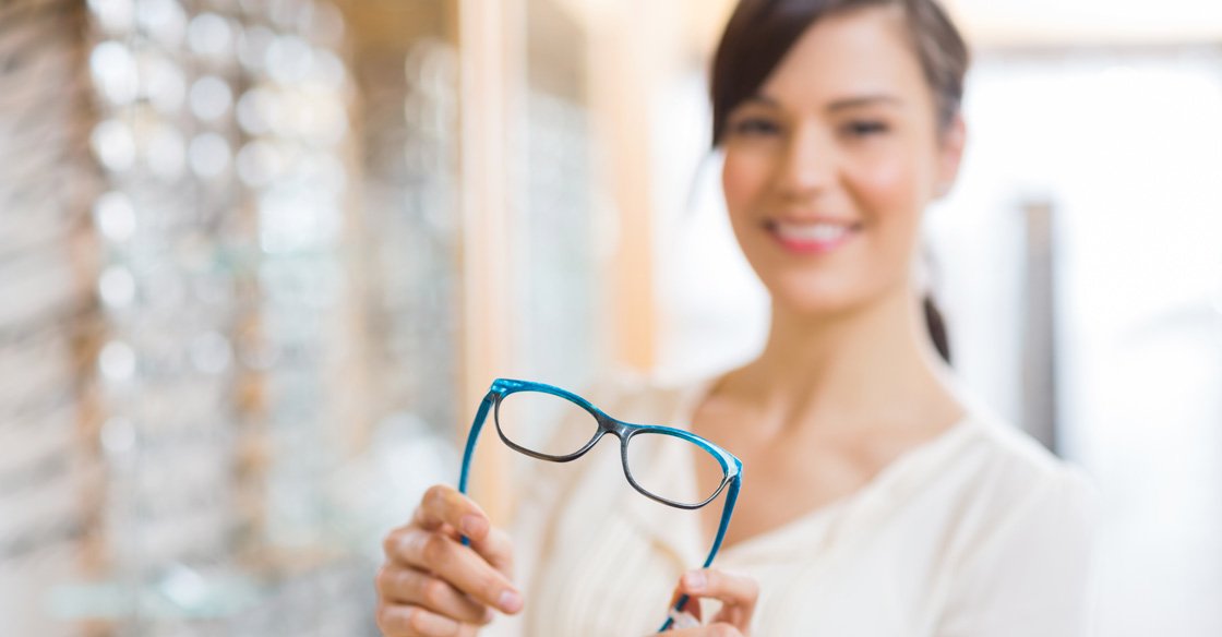 woman holding up a pair of glasses with a blue frame around them