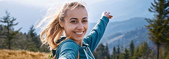 young blonde woman smiling on top of a mountain