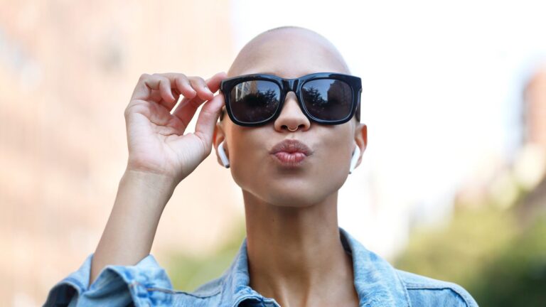 young woman wearing designer sunglasses with airpods in listening to music