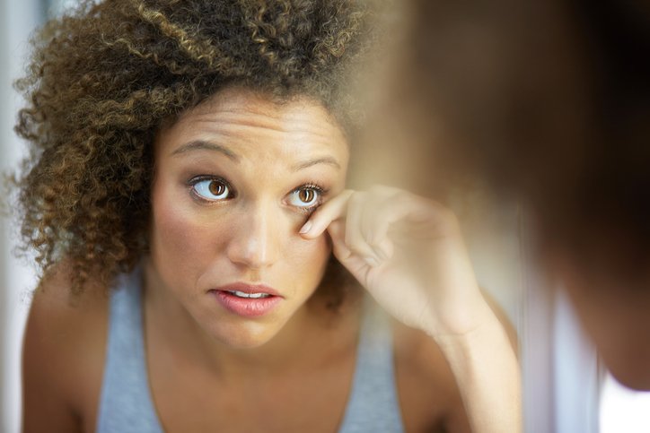 woman rubbing her eye in the mirror