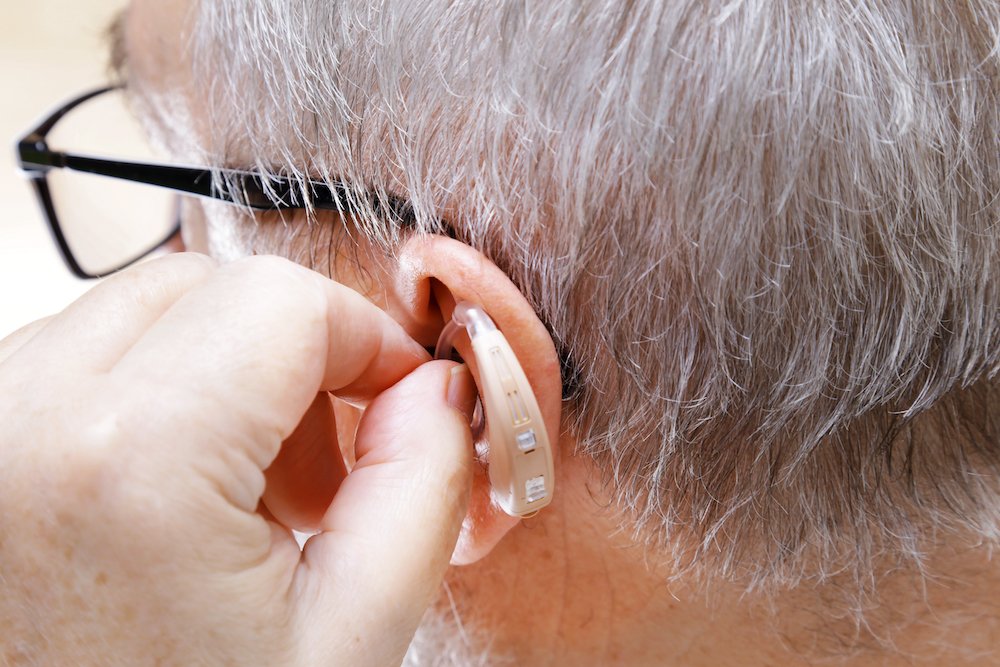 male wearing glasses putting in his hearing aid