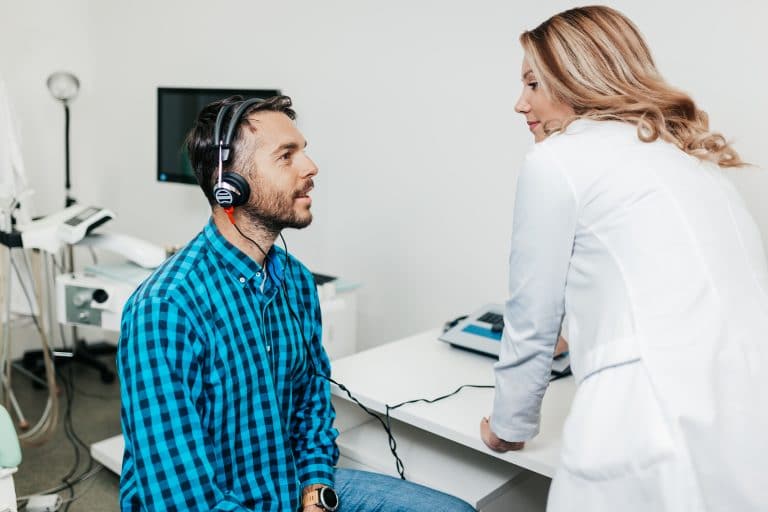 woman doctor giving a younger male a hearing test