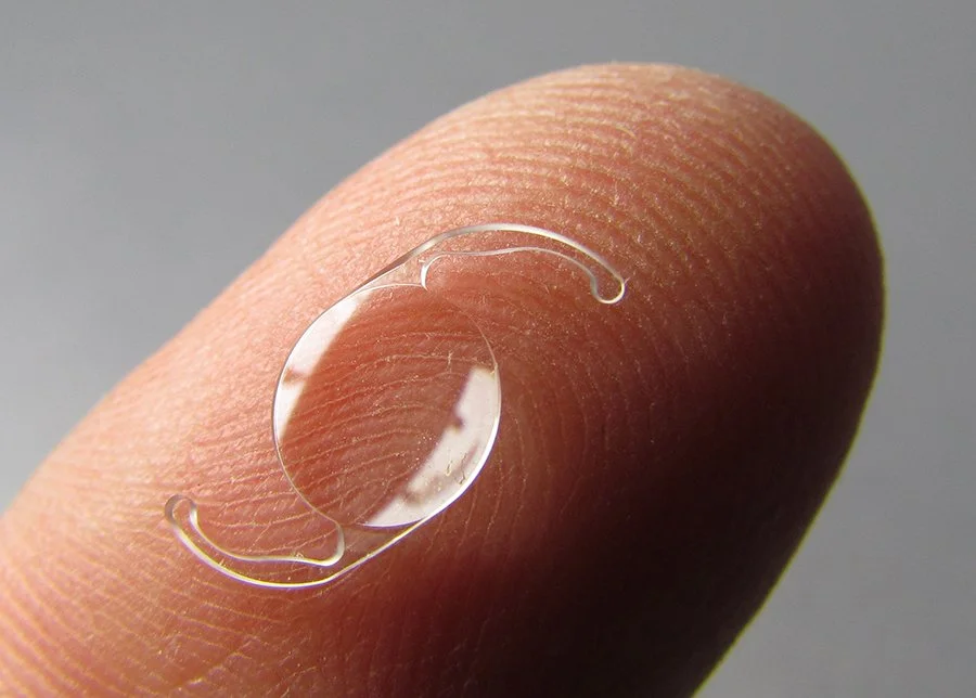 Toric lens used in cataract surgery held on a finger