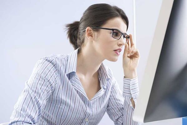 woman wearing glasses looking at her computer screen