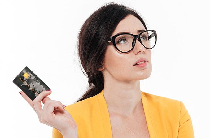 woman wearing glasses holding a credit card up