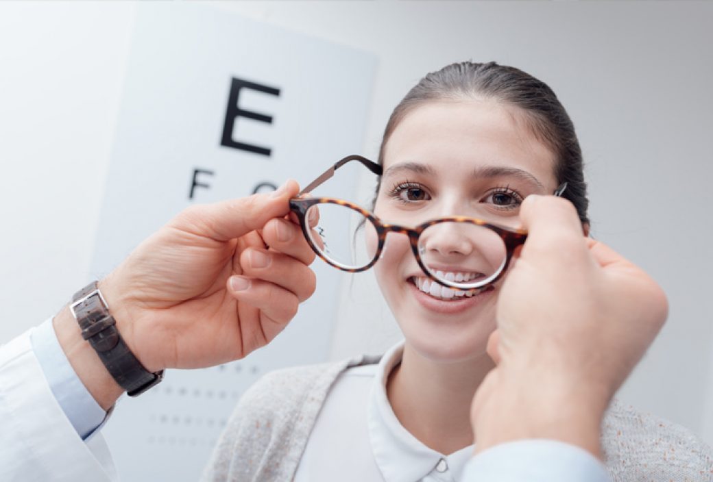 doctor putting glasses on a young ladys face