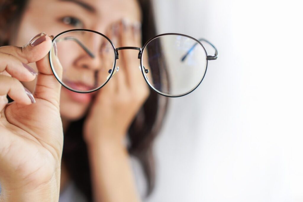 young lady holding up her eyeglasses