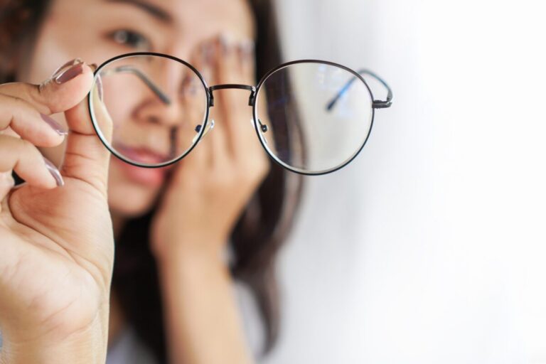 young lady holding up her eyeglasses