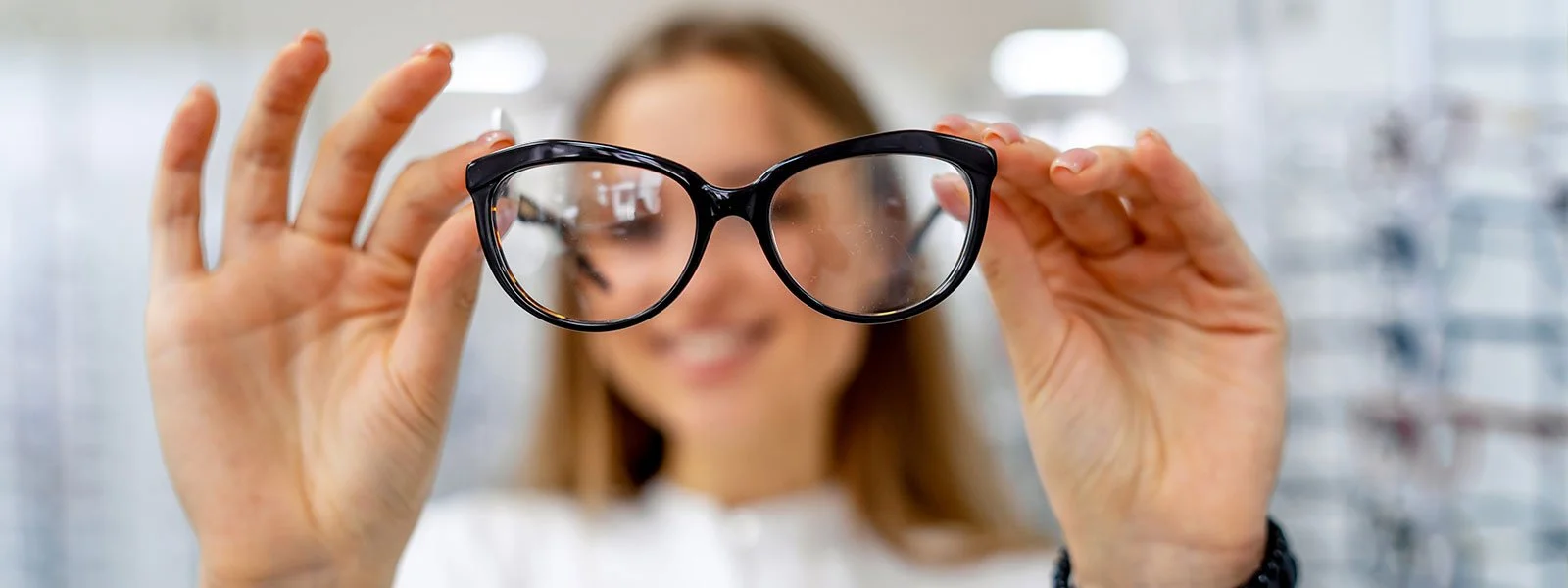 Woman holding up a pair of glasses with the area inside the lenses being clear and the outside is blurry