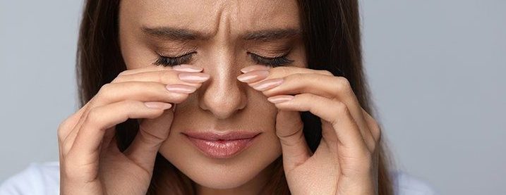 woman tearing and holding her fingers to her eyes