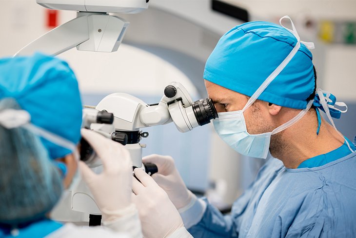 two doctors looking through a scope preforming cataract surgery