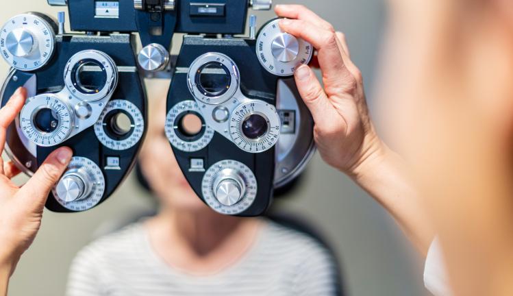 Woman sits with equipment at an eye exam