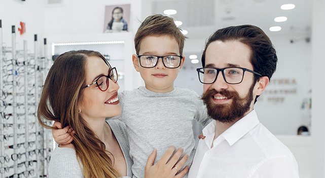 man and woman holding a child all wearing glasses in an optical shop