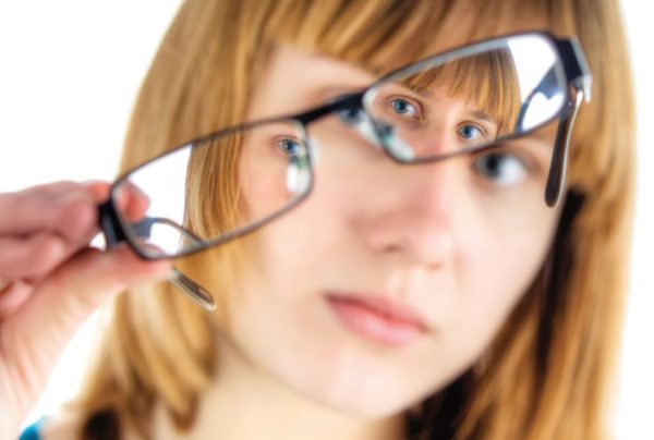 A girl with blonde hair looking through her glasses
