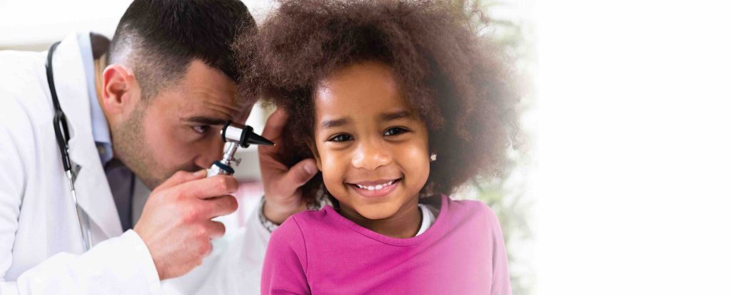 Young girl gets her ears checked by a doctor