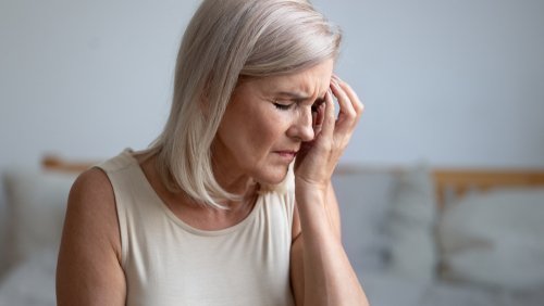 Woman in pain touching her hand to her forehead