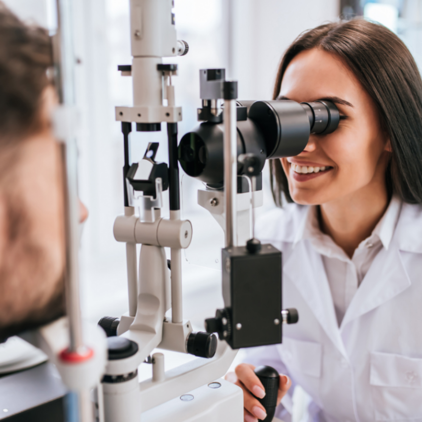 Attractive female doctor is checking the eye vision of handsome young man in modern clinic