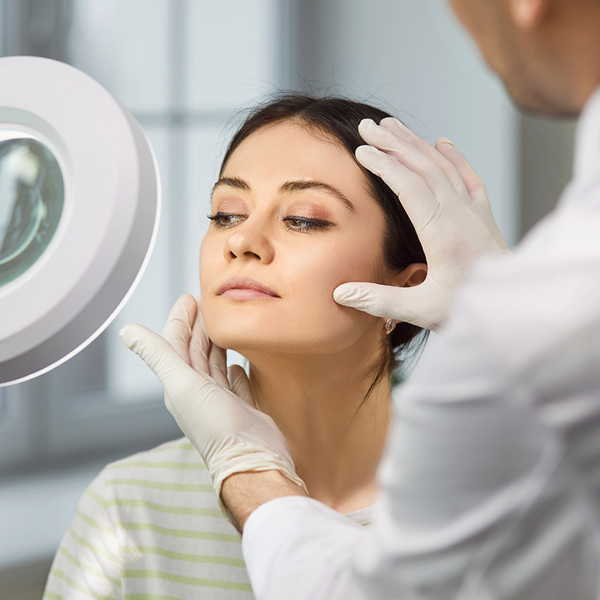 Beautiful-cheerful-young-lady-sitting-in-beauty-clinic-and-having-consultation-about-plastic-surgery-with-a-male-doctor-cosmetologist