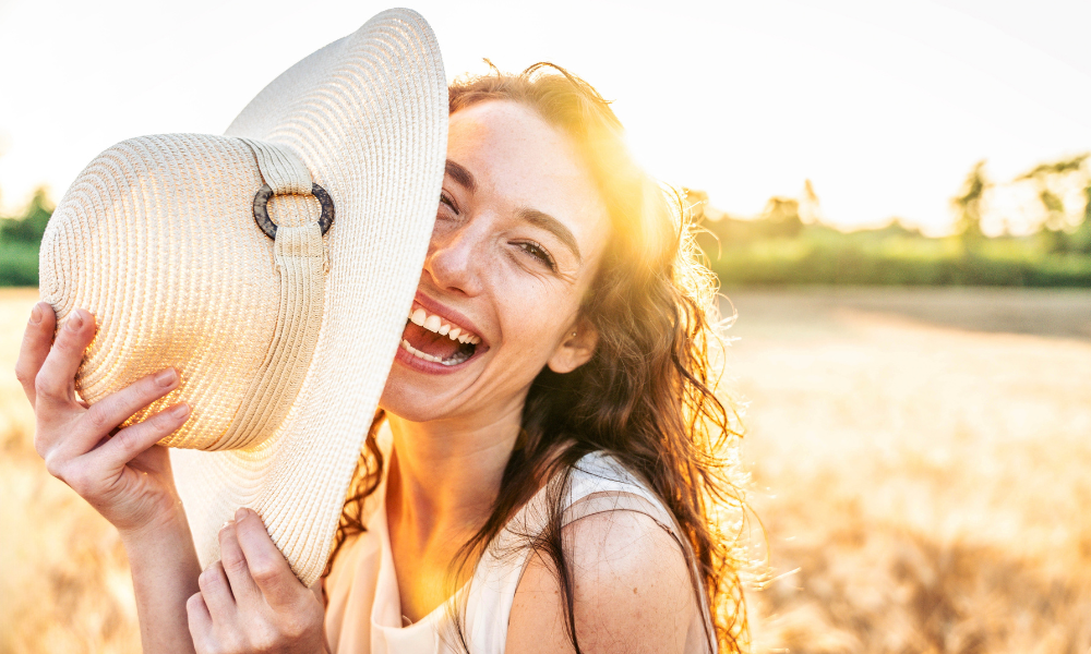 Beautiful young woman smiling at camera with sunset on background - Portrait of happy girl enjoying summer vacation - People life style concept
