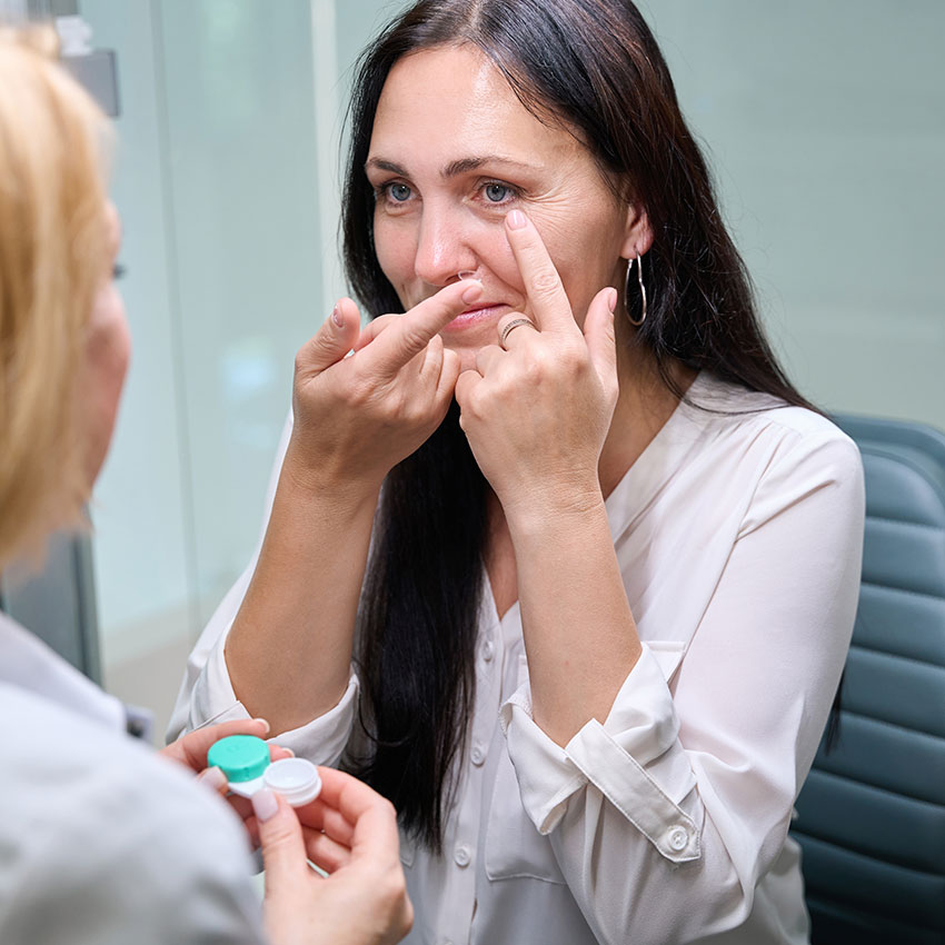 Female-patient-putting-in-ophthalmic-lenses-under-supervision-of-optometrist
