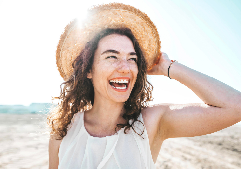 Happy beautiful young woman smiling at the beach side healthy lifestyle concept with female laughing outside