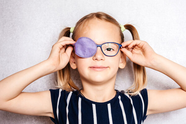 Happy-little-girl-wearing-glasses-and-eye-patch-or-occluder,-amblyopia-(lazy-eye)-treatment