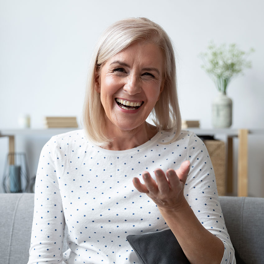 Happy-mature-blonde-lady-sitting-on-couch,-holding-video-call-with-friends,-head-shot-close-up-portrait