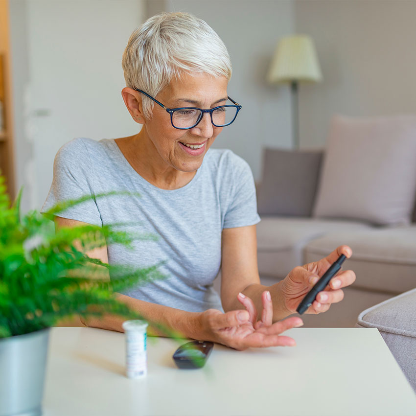 Happy-mature-woman-with-glucometer-checking-blood-sugar-level-at-home