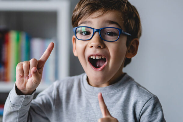 One-small-happy-caucasian-boy-close-up-looking-to-the-camera-while-standing-at-home-wearing-eyeglasses