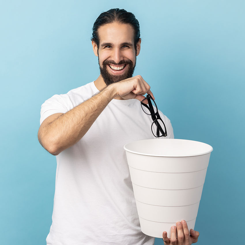 Portrait-of-man-with-beard-wearing-white-T-shirt-throwing-out-eyeglasses-into-rubbish-bin