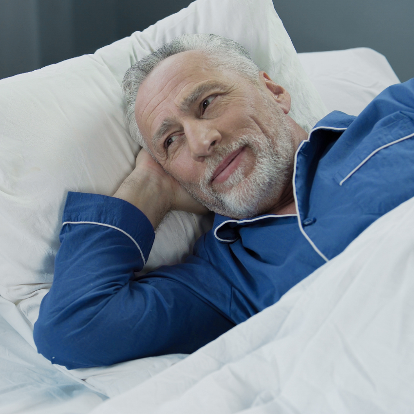 Senior male waking up and smiling after comfortable healthy sleep, health care