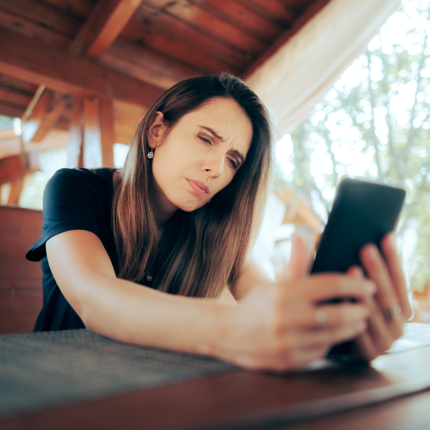 Woman Squinting Trying to Read Small Text on her Phone Lady suffering from presbyopia aging vision problems