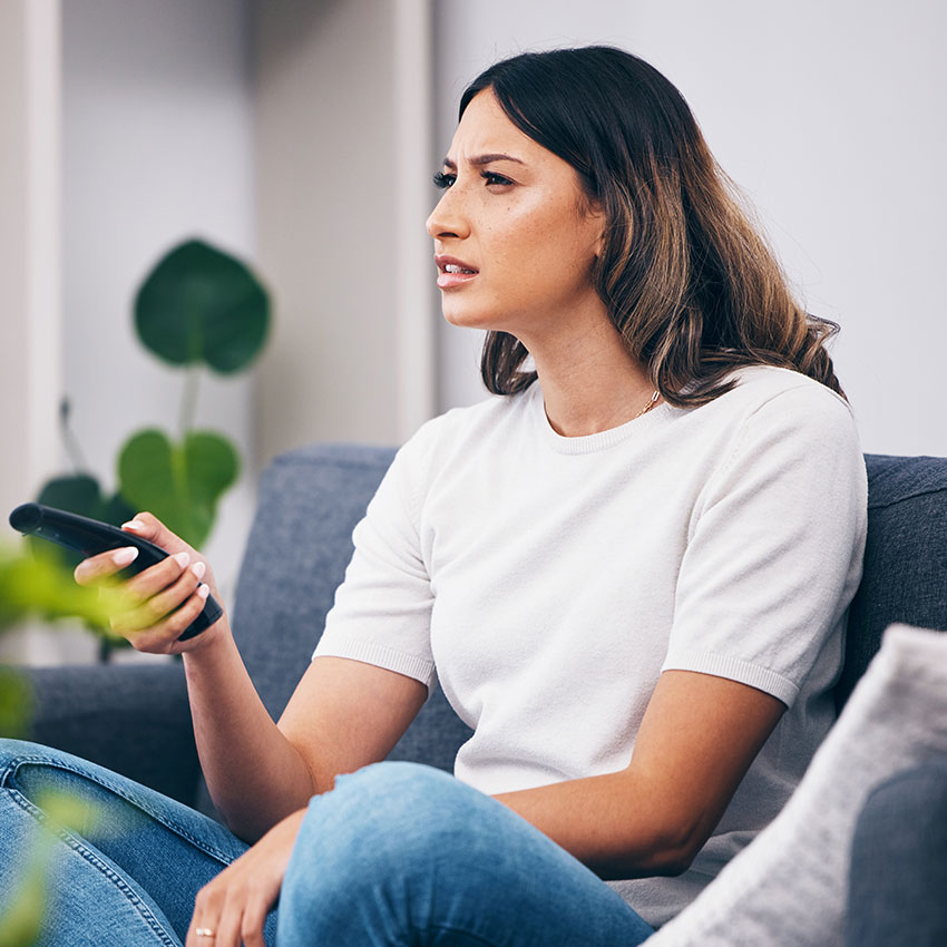 Woman-confused,-watching-tv-and-remote-control,-relax-at-home-and-squint-with-vision-problem-and-streaming-movie