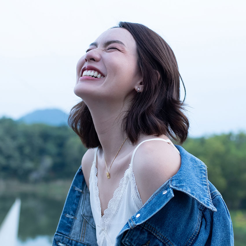 Woman-smiling-with-perfect-smile-and-white-teeth-in-a-park-and-looking-at-camera,-Portrait