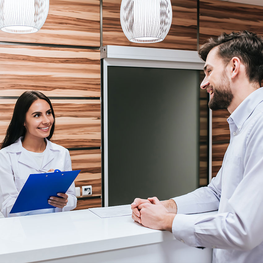 Young-female-doctor--and-handsome-patient-are-standing-on-reseption-desk-in-modern-clinic