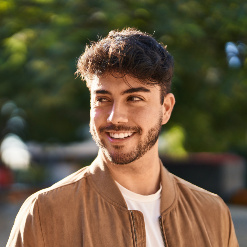 Young hispanic man smiling confident looking to the side at park