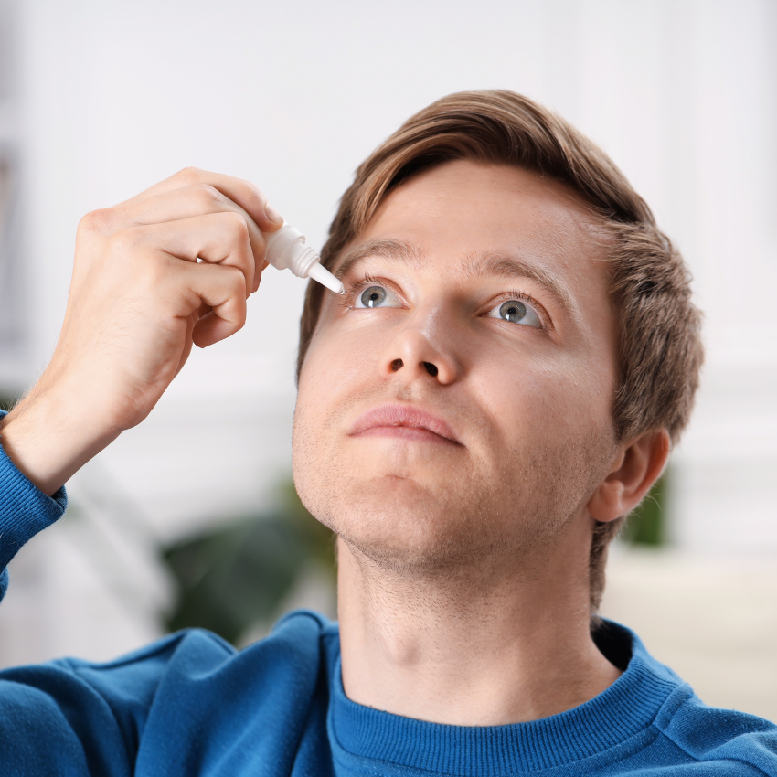 Young man applying eye drops at home