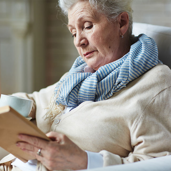 Calm-winter-evening-by-fireplace-pretty-senior-woman-sitting-back