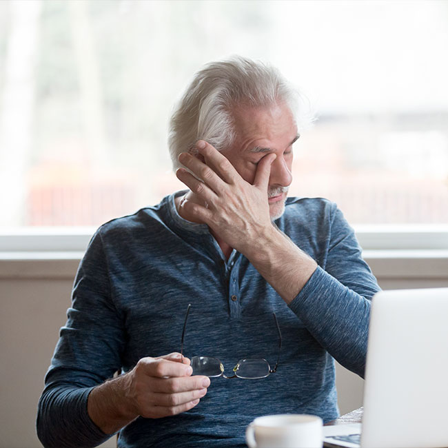 Fatigued-mature-old-man-taking-off-glasses-suffering-from-tired-dry-irritated-eyes-after-long-computer-use