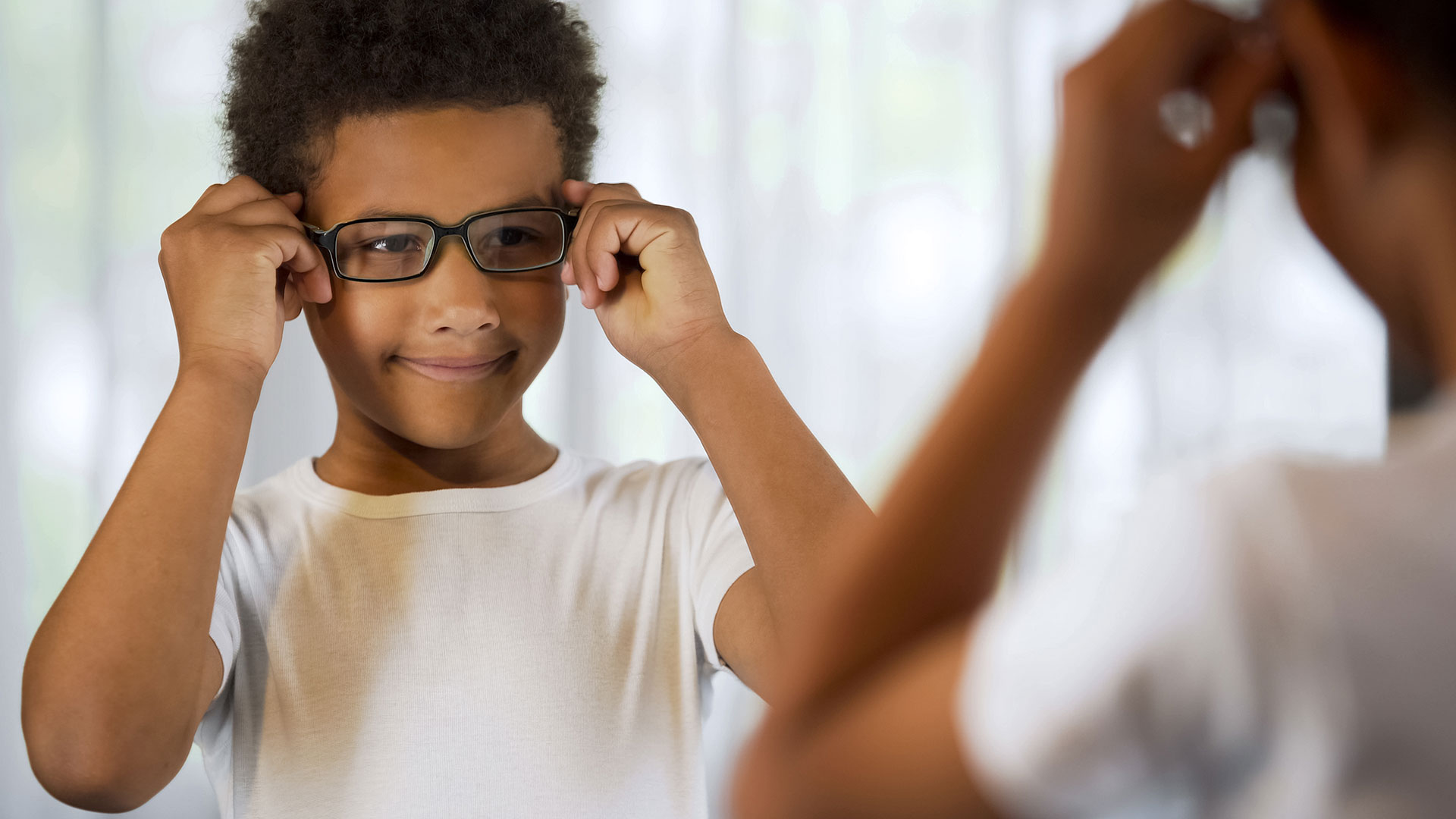 Happy-little-kid-trying-on-eyeglasses,-looking-in-mirror-satisfied-good-eyesight