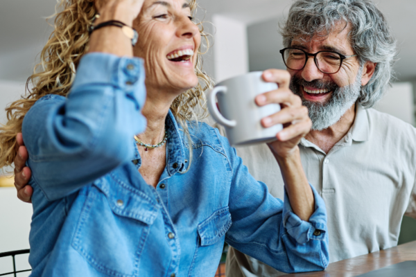 Elderly couple sitting at desk with coffee laughing