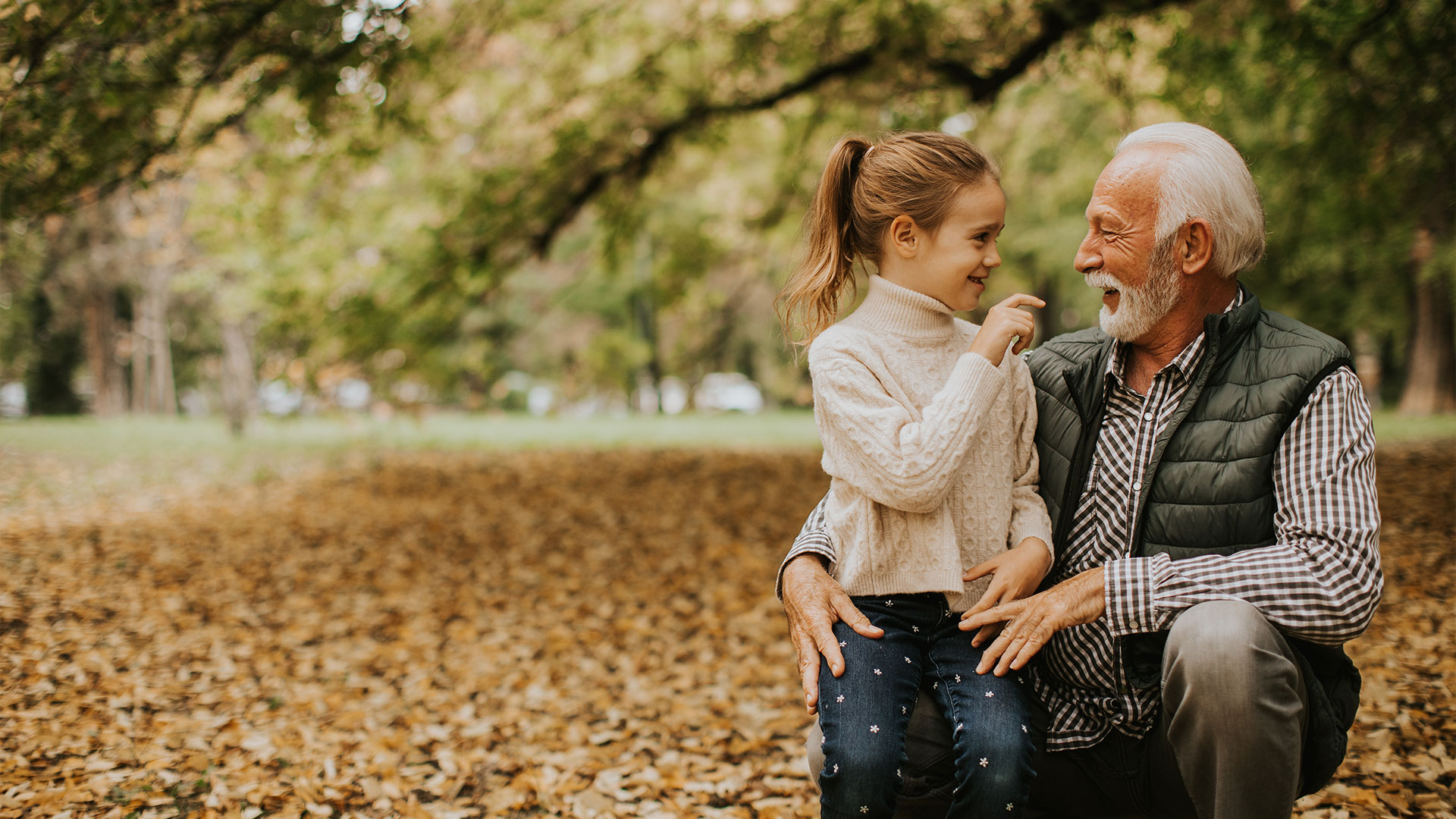 Grandfather-spending-time-with-his-granddaughter-in-park-on-autumn-day