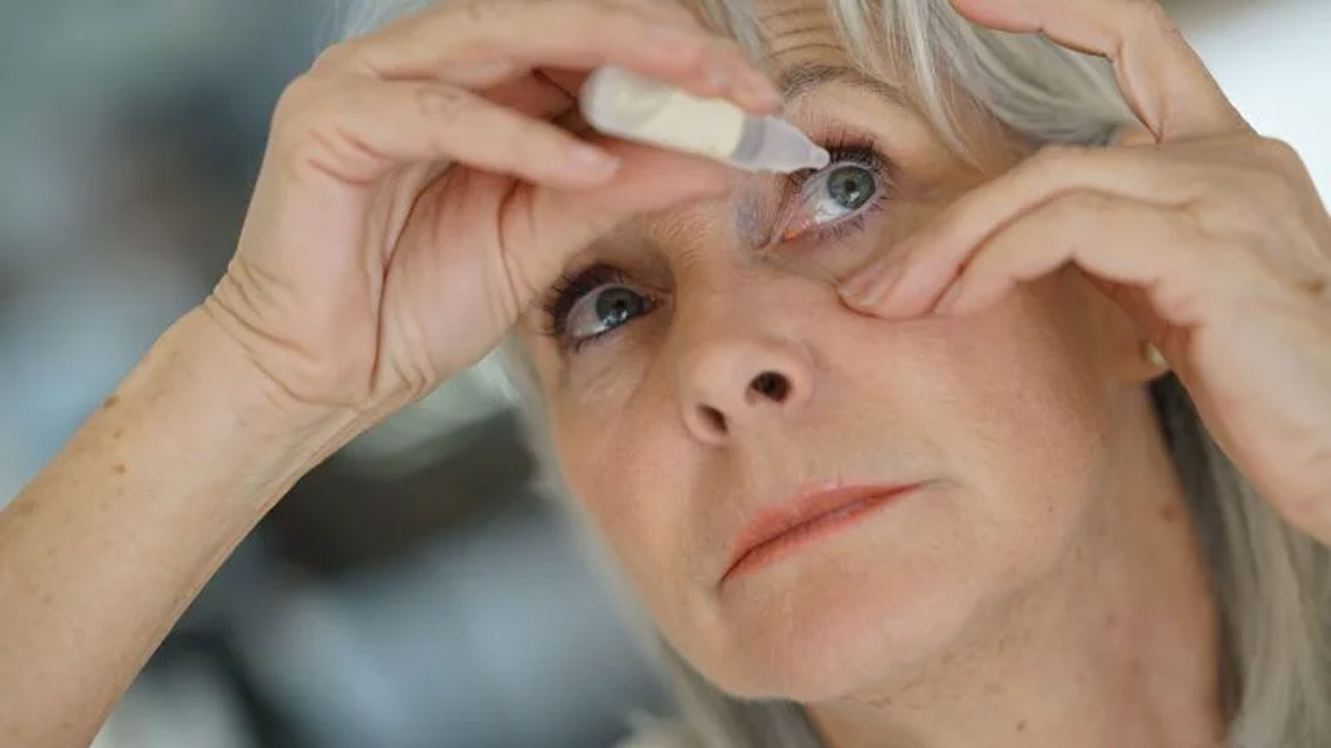 Woman applies eye drops