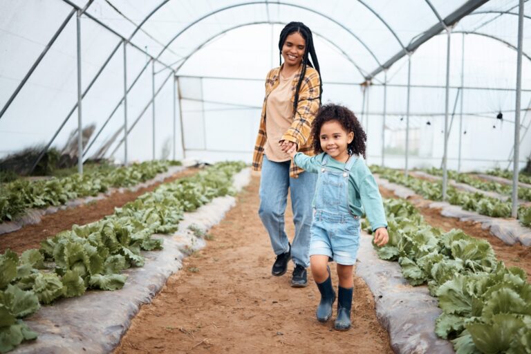 Mother and daughter walking in a greenhouse and smiling.