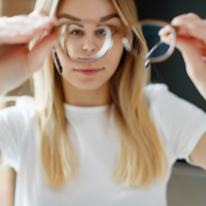 A woman has vision problems, squints when trying to see something, takes off her glasses, is isolated