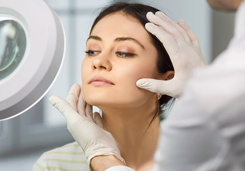 Beautiful-cheerful-young-lady-sitting-in-beauty-clinic-and-having-consultation-about-plastic-surgery-with-a-male-doctor-cosmetologist