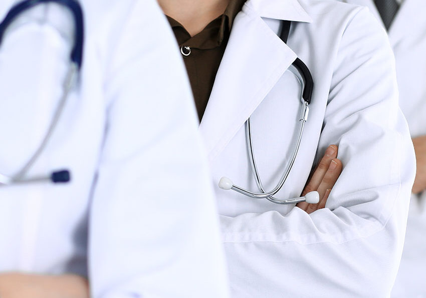 Group-of-modern-doctors-standing-as-a-team-with-arms-crossed-in-hospital-office