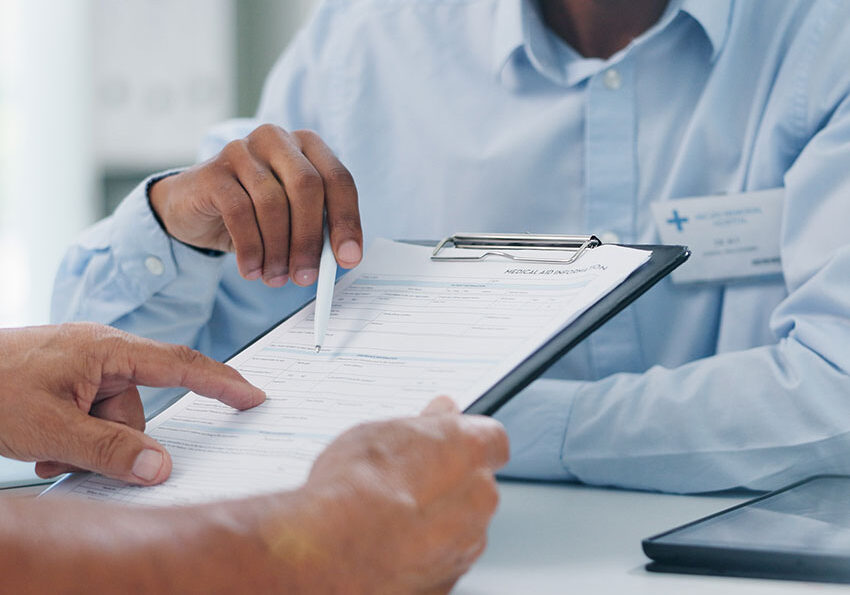 Man,-doctor-and-hands-with-form-in-consultation-for-signature,-application-or-health-insurance-at-hospital