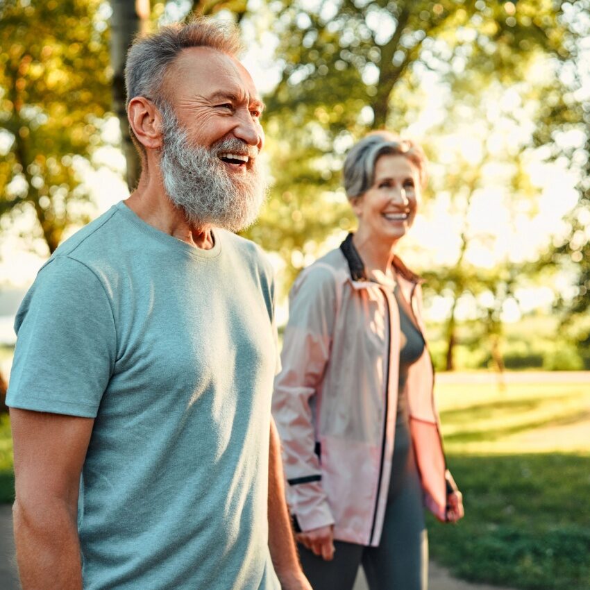 Elderly couple walking outside in park on a sunny day