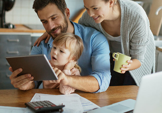 Young-family-using-tablet-with-documents-on-desk